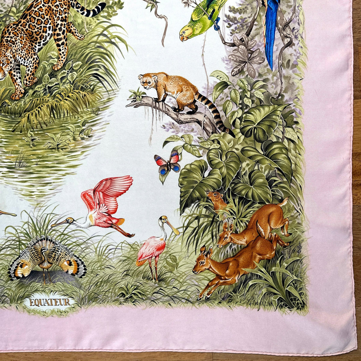 Carré Hermès Équateur de Robert Dallet, 90 cm en soie : coin aux cervidés, ara bleu et titre Equateur, ourlet roulotté