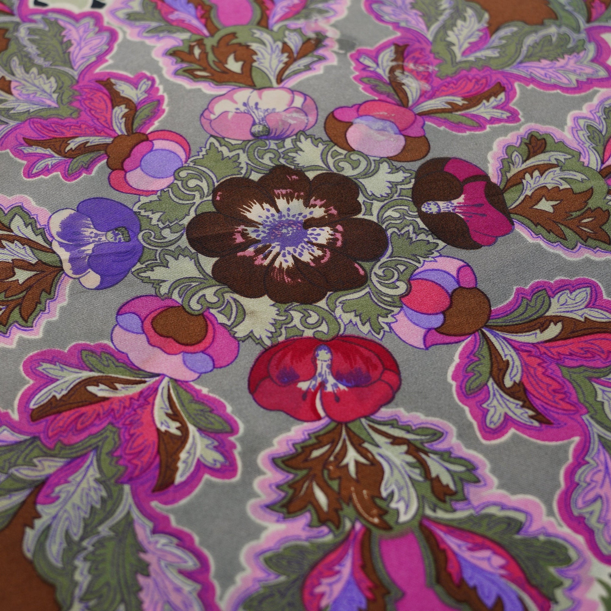 Gros plan sur la richesse des couleurs des fleurs d'anémones dans les tons rose vif et prune sur le foulard vintage Hermès.