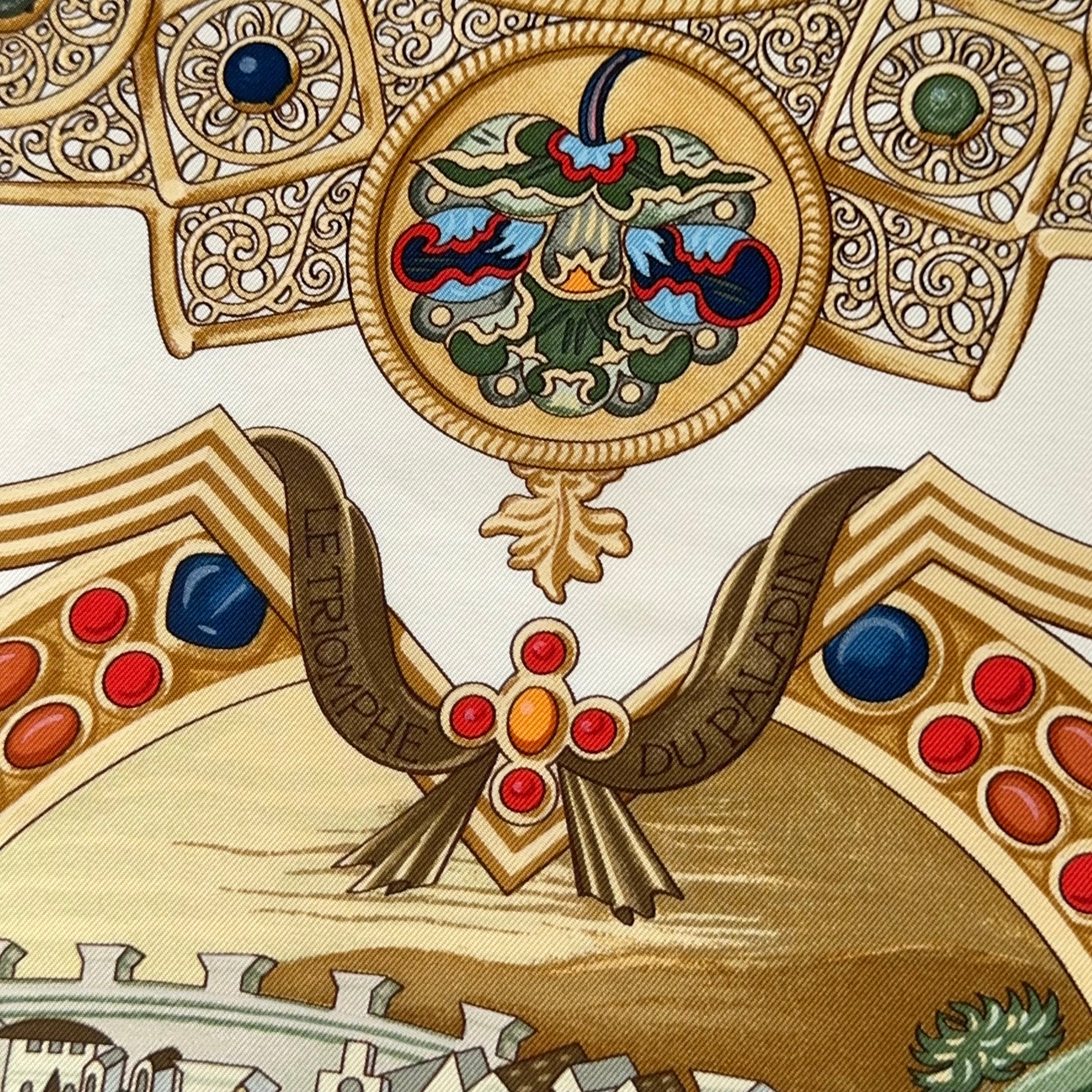 Zoom sur le titre du carré "Le Triomphe du Paladin" inscrit dans un ruban doré, au-dessus d'une croix byzantine ornée de rubis.