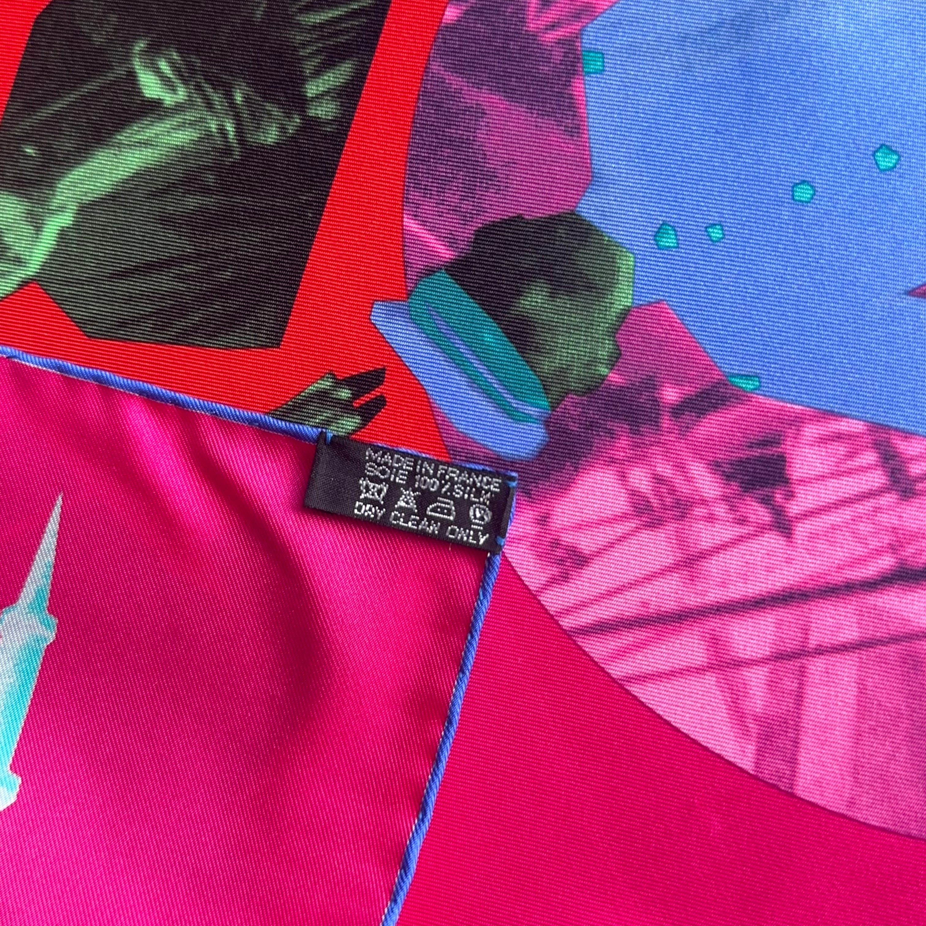 Étiquette de composition "Made in France 100% Silk" cousue sur le bord roulotté main de couleur bleu roi contrastant avec le fond fuchsia.