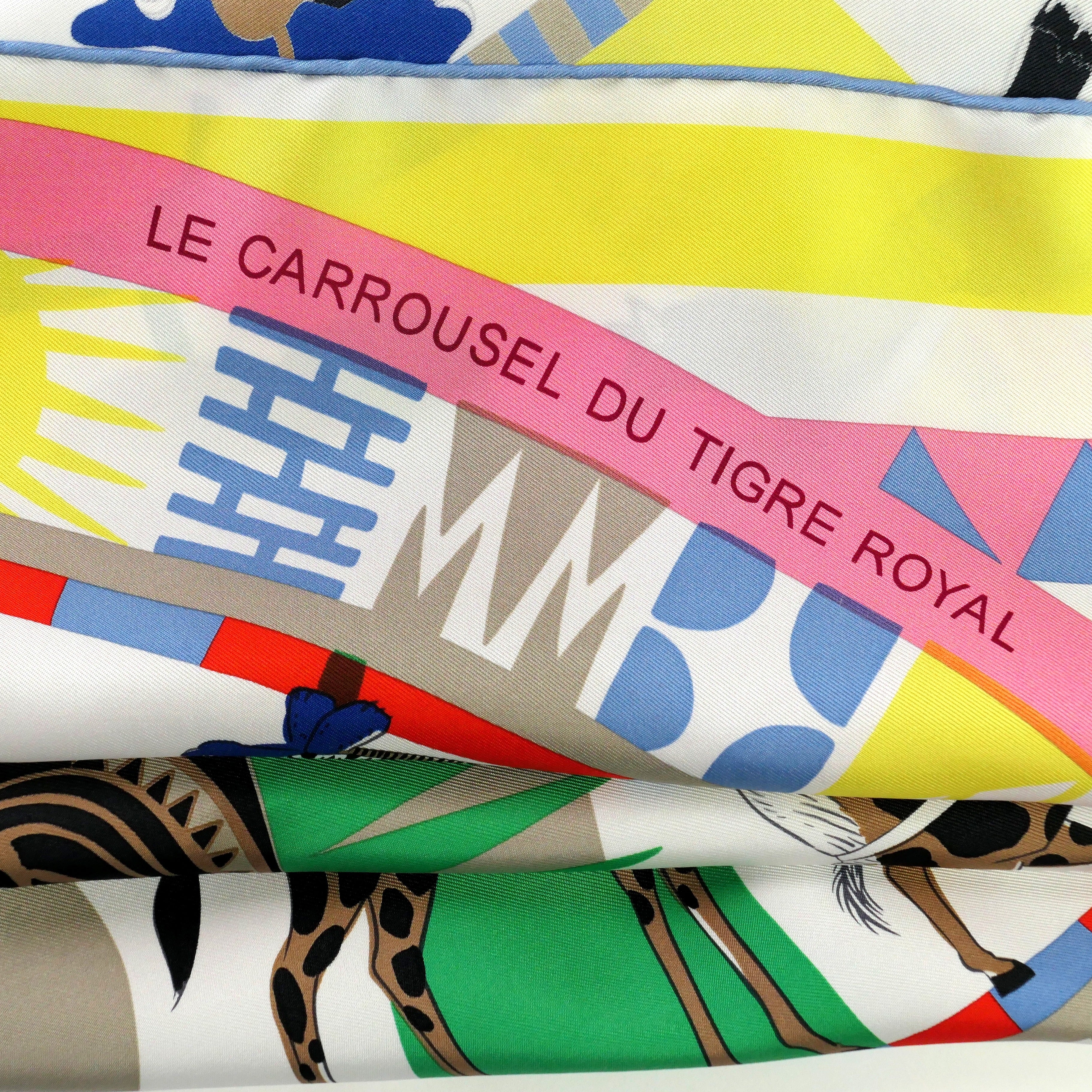 Carré Hermès Le Carrousel du Tigre Royal de Katie Scott, 90 cm soie, détail du titre sur bandeau rose