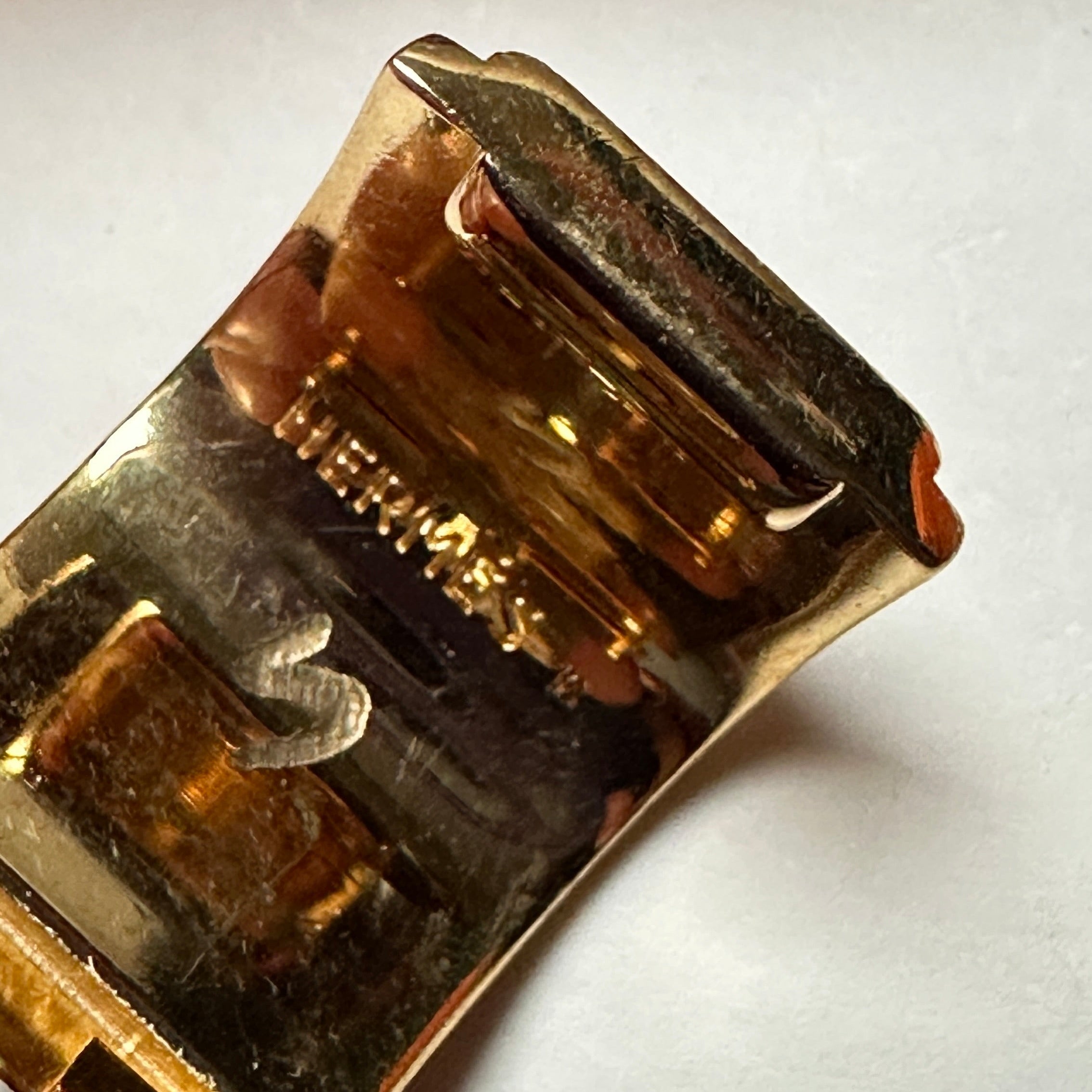 Macro sur la signature Hermès et le marquage S (Ventes Privées) gravés à l'intérieur de la monture dorée.