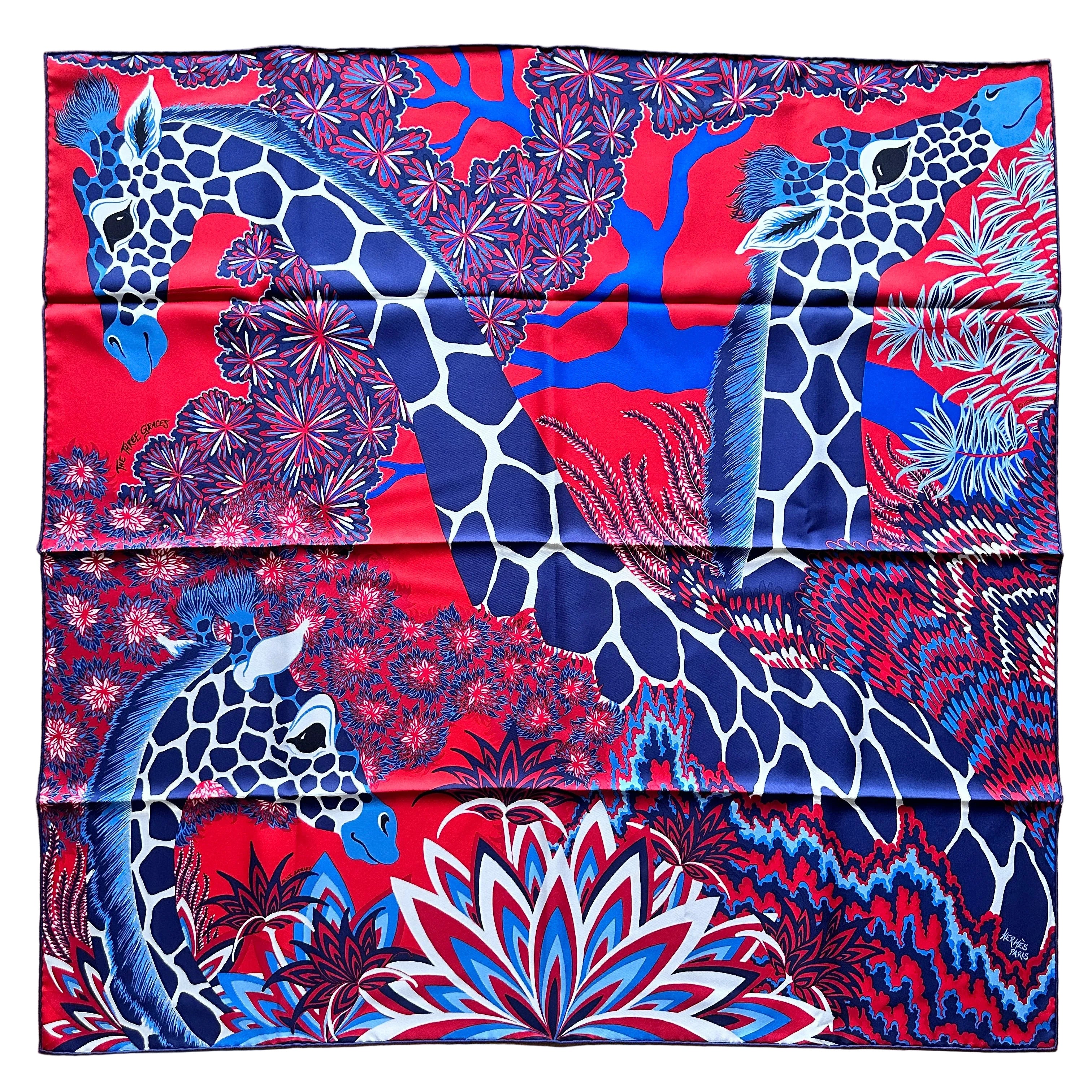 Foulard Hermès The Three Graces fond rouge girafes bleues à plat